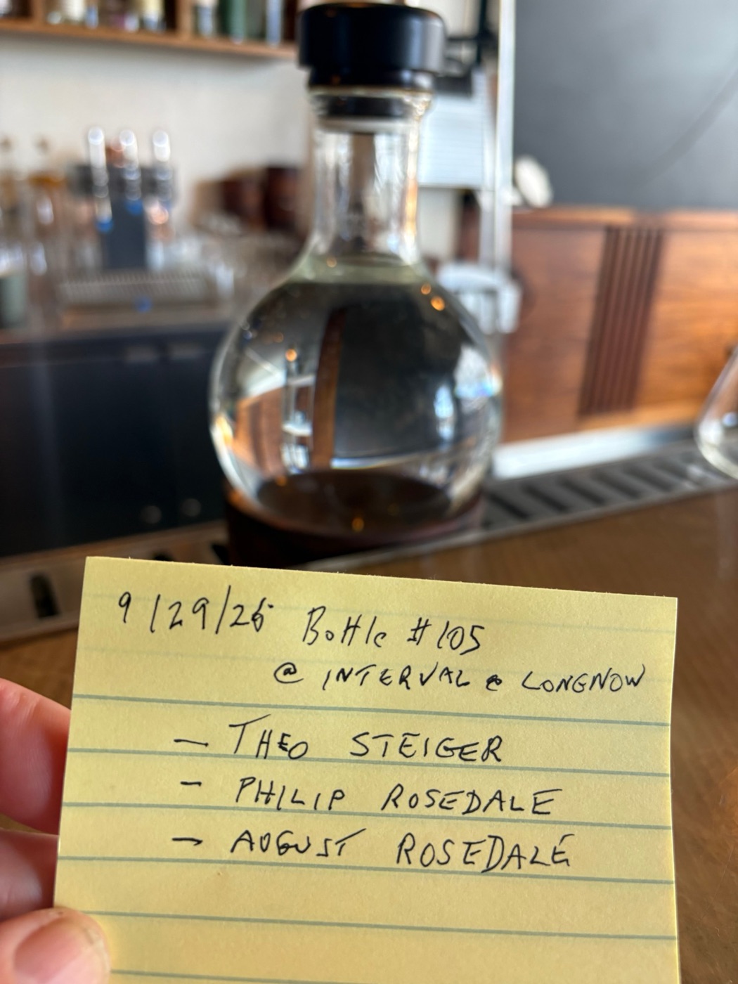 Handwritten note in front of the refilled bottle: 9/29/26, Bottle #105 at Interval at Long Now, Theo Steiger, Philip Rosedale, August Rosedale